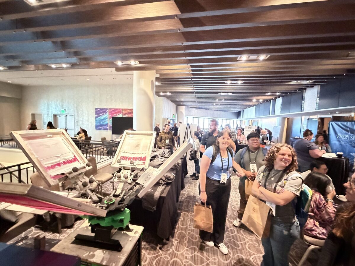 Busy convention floor crowd moving between booths under bright expo lighting